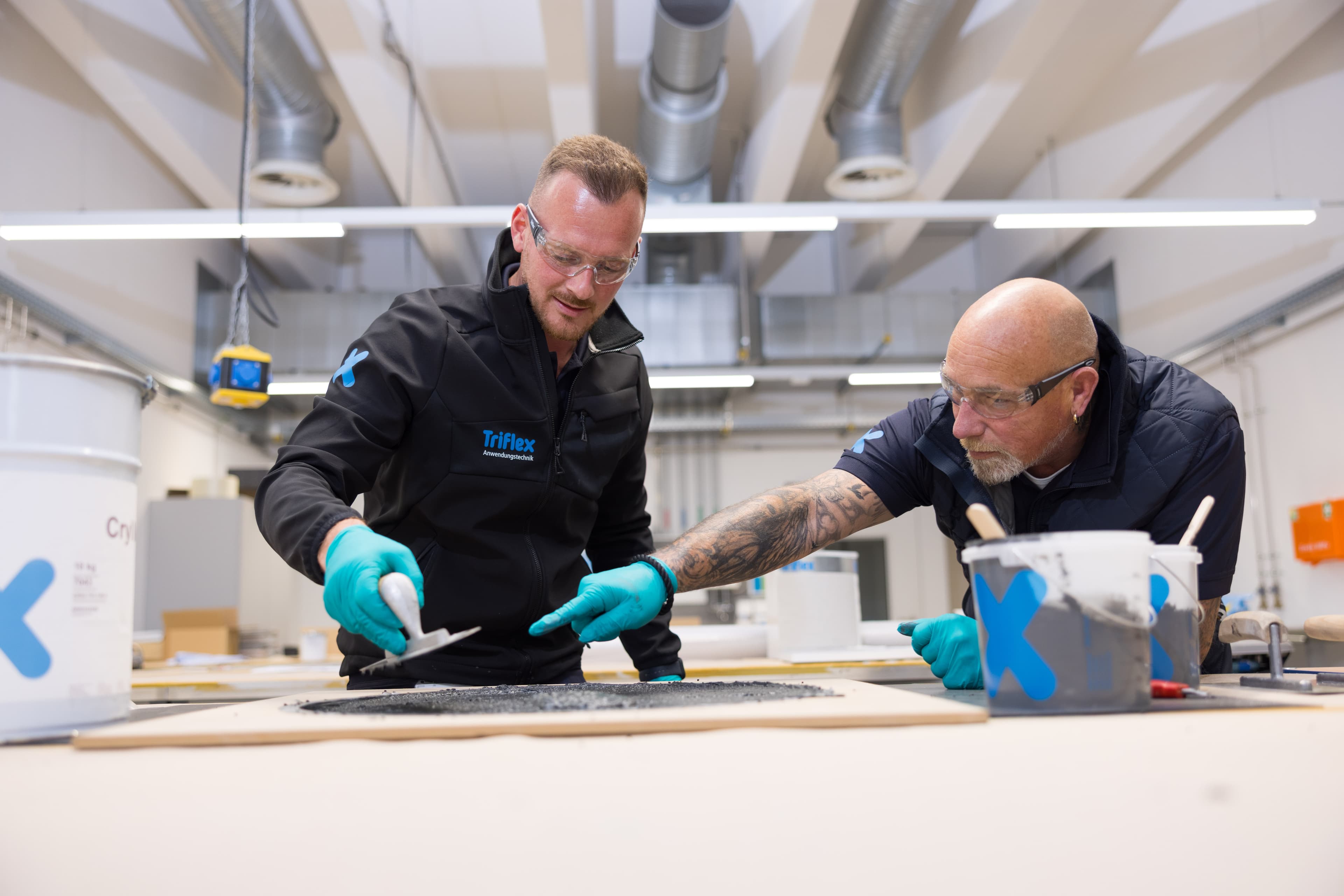 Mitarbeitende der Anwendungstechnik bei Triflex prüfen Materialien im praktischen Umfeld.