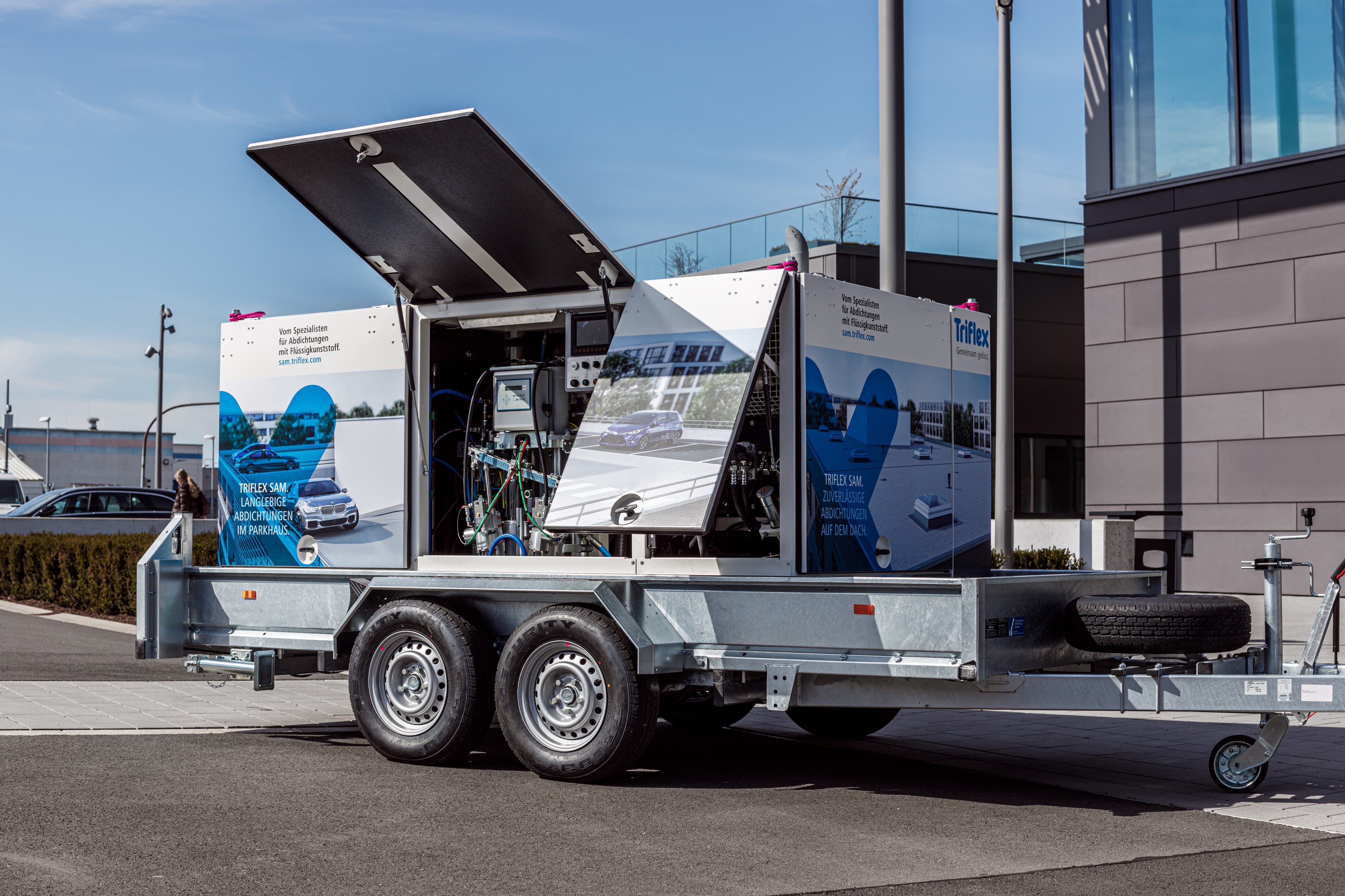 Mobile processing trailer equipped with mixing and conveying systems for liquid-applied waterproofing on a construction site.