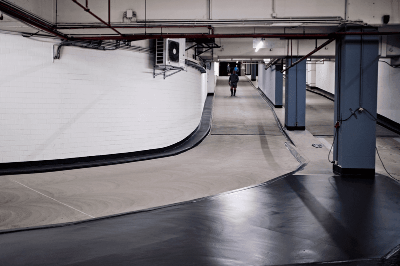 Sauber sanierter, hell beleuchteter Tiefgaragenbereich mit frisch beschichtetem Boden und klar abgegrenztem Fahrweg.