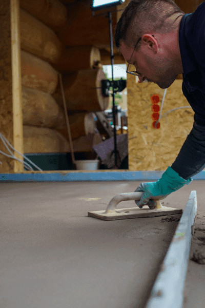 Verarbeiter glättet Estrichfläche mit Kelle auf Baustelle